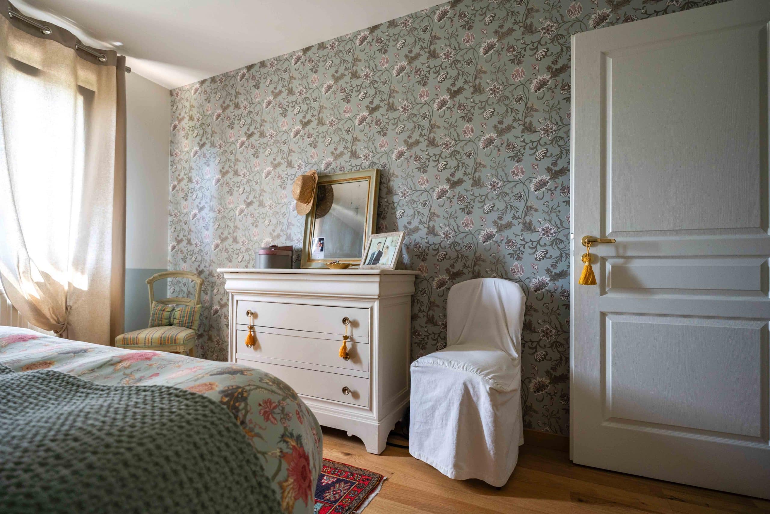 Chambre décorée de style vintage avec papier peint floral, commode blanche et objets personnels – Aléna Zuliani Azai architecture