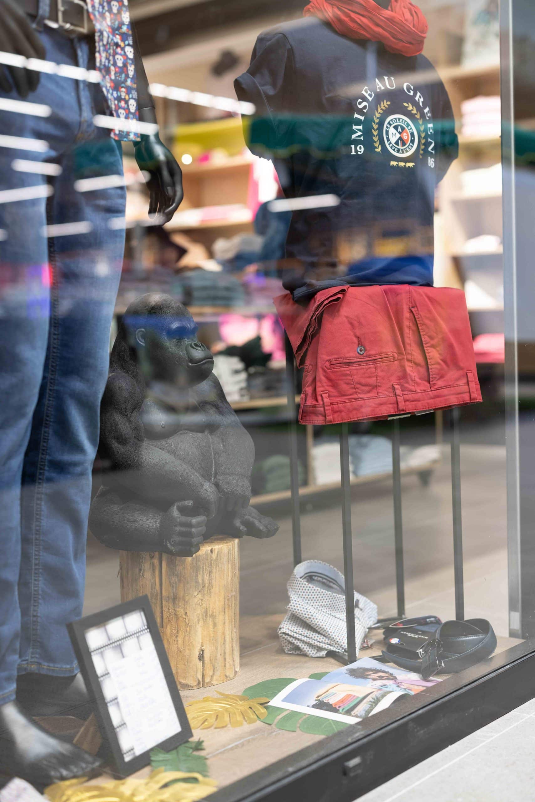 Vitrine originale de la boutique Osmose by Charly avec statue de gorille, tronc en bois brut et mise en scène de vêtements, imaginée par Alena Zuliani – Azai, architecte d’intérieur en Alsace